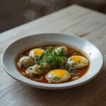A complete savory dumpling ramen bowl served on a table with soft-boiled eggs and fresh greens.