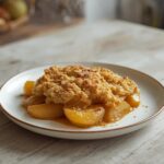 A single serving of apple crumble in a small dish, featuring a golden baked topping and bubbly apple filling.