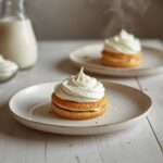 A plate of adorable mini slagroomgebakjes with whipped cream and a dusting of powdered sugar, showing a complete no bake dessert.