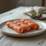 Elegant smoked salmon roll ups with cucumber and cream cheese on a serving platter.