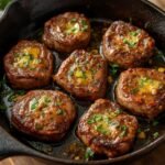 A rustic cast iron skillet filled with delicious garlic butter steak bites garnished with parsley
